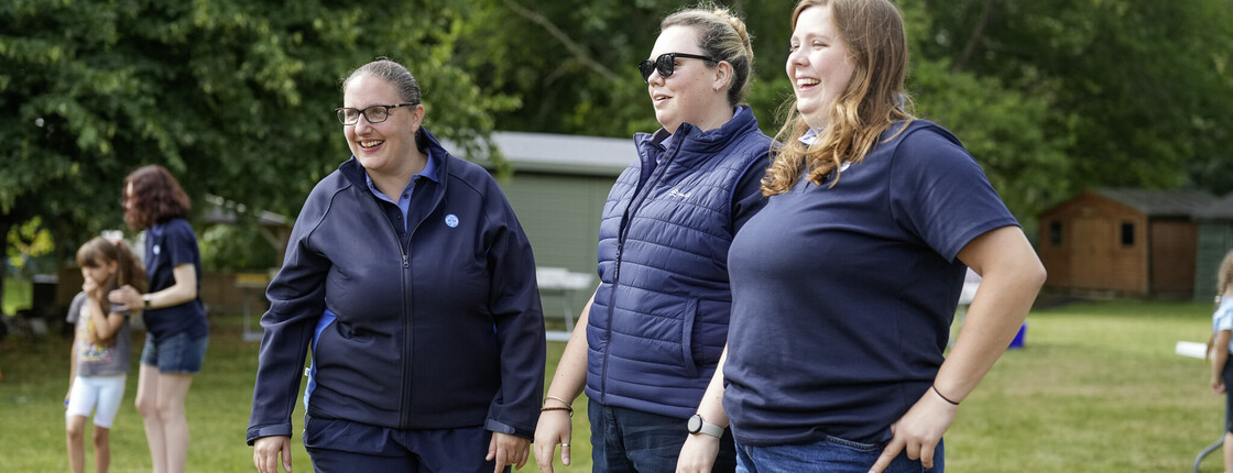 3 adult volunteers standing and smiling