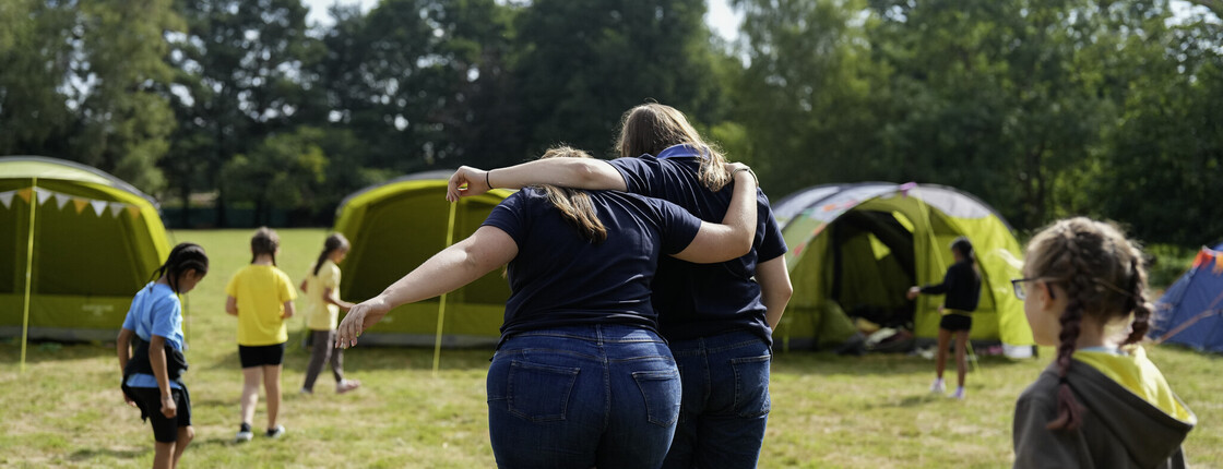 Volunteers embracing outdoors, facing away from camera